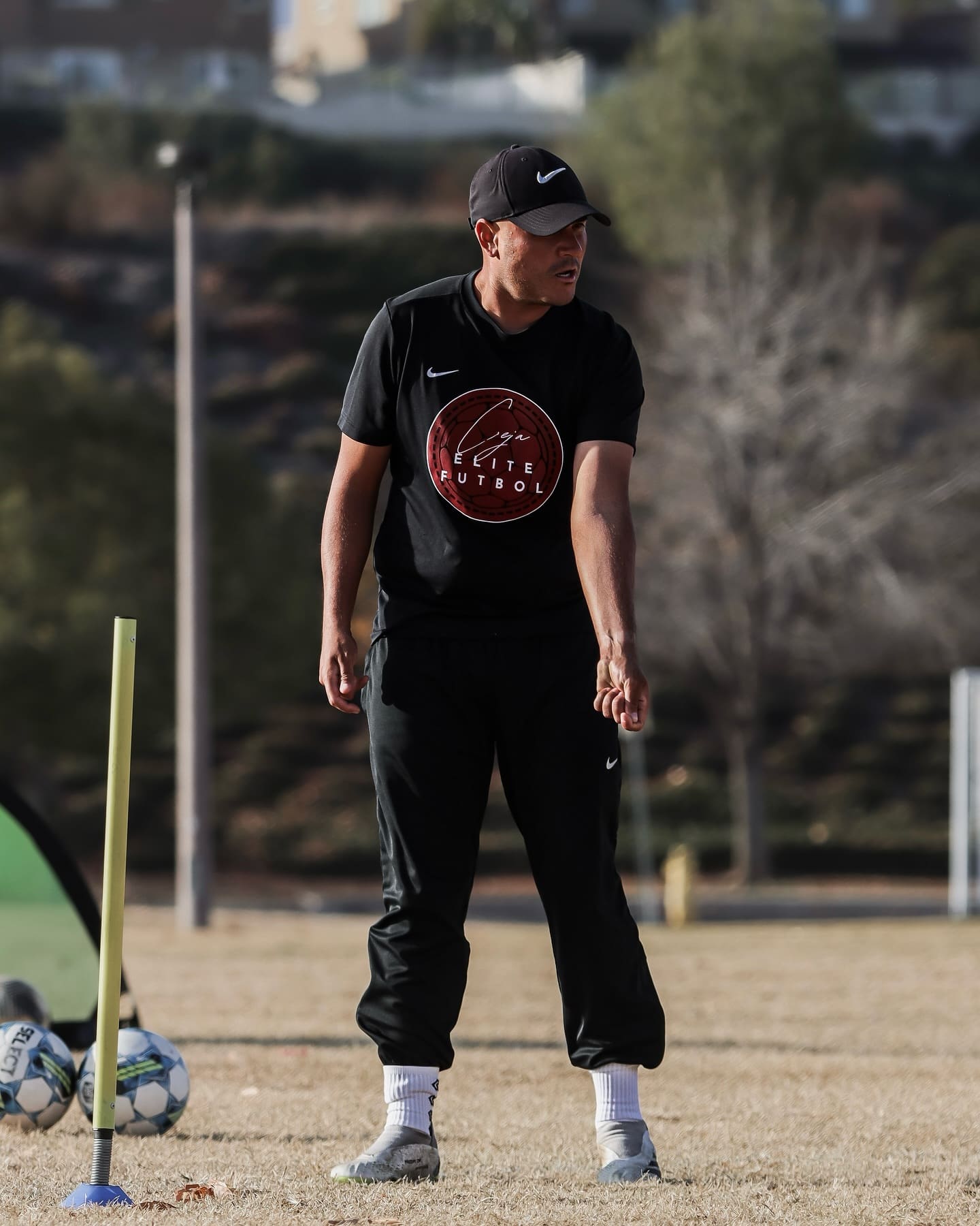 Coach Ceja running a session, training poles and balls at his feet