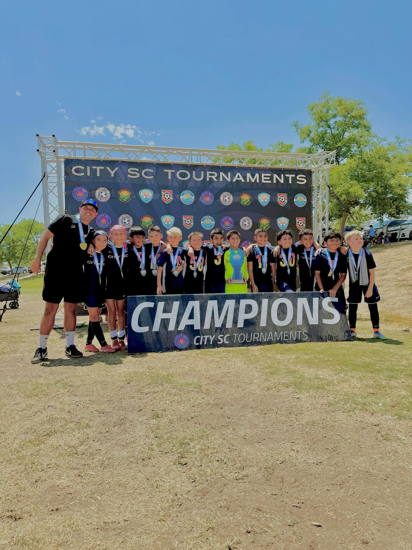 Coach Ceja and his team with a tournament champions banner