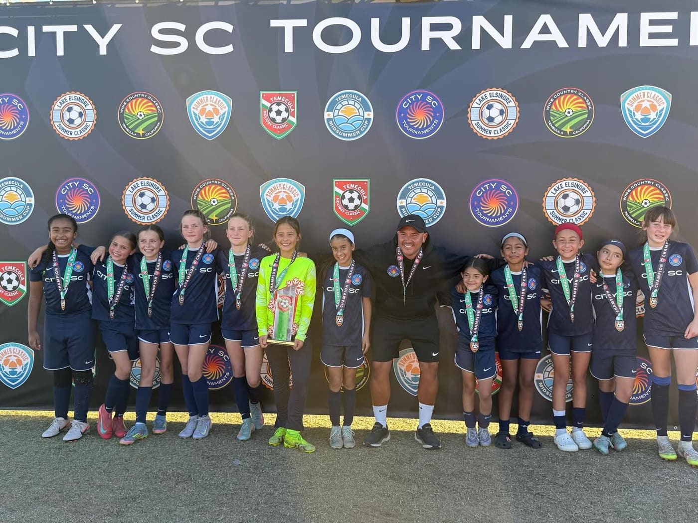 Coach Ceja and players with medals at City SC Tournaments